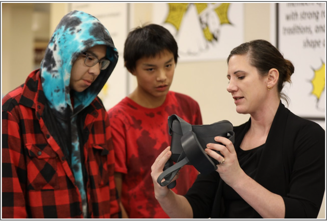 Lindsey Boechler showing two youths how to use a VR headset.